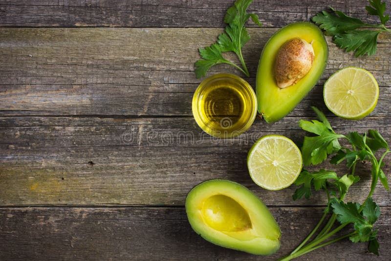 Essen hintergrund mit frischen Bio-avocado, Limette, Petersilie und Olivenöl auf den alten Holztisch, Ansicht von oben, Kopie, Raum.