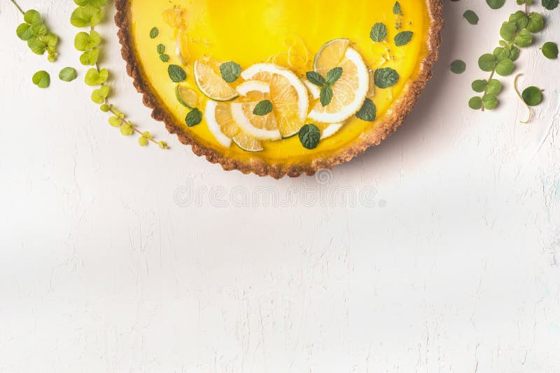 Food background with lemon tart topped with citrus slices and zest on white table background, top view. Copy space. Close up. stock photos