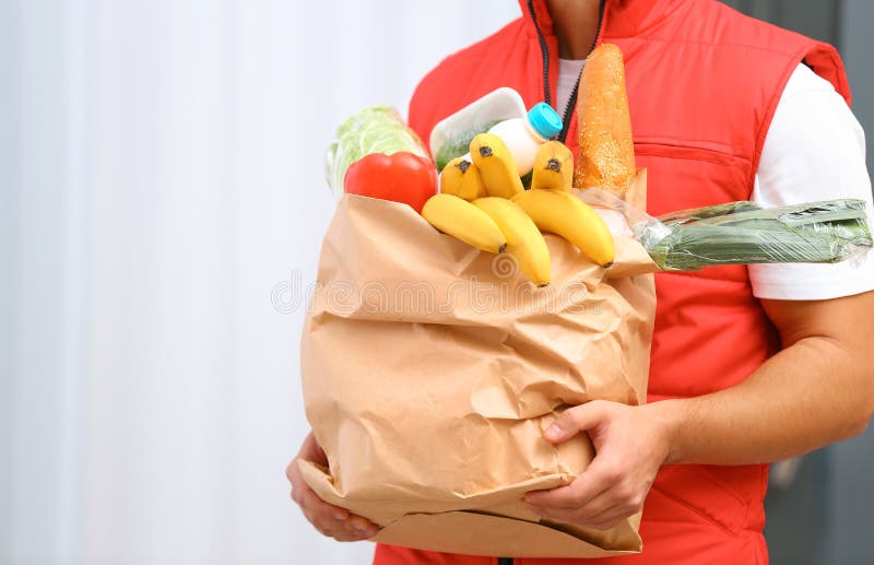 Food Delivery Courier Holding Paper Bag with Products, Closeup. Space