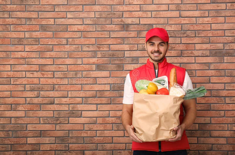 Food Delivery Courier Holding Paper Bag with Products Stock Photo