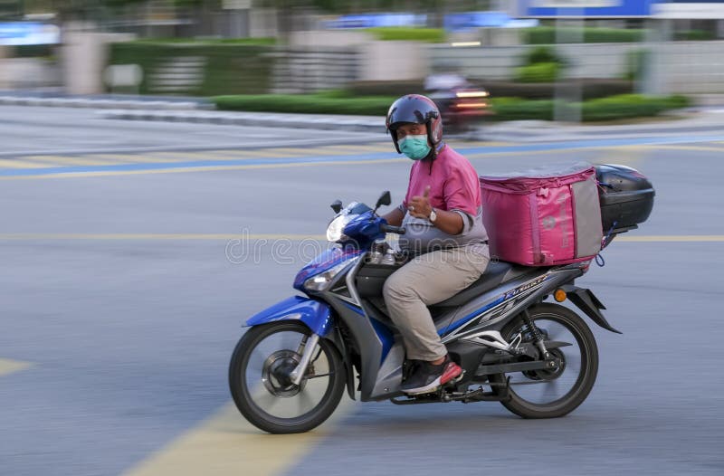 KUALA LUMPUR, MALAYSIA - MARCH 25, 2020: Panning motion blur of Foodpanda rider rushing delivering food. Food delivery service through the mobile application. KUALA LUMPUR, MALAYSIA - MARCH 25, 2020: Panning motion blur of Foodpanda rider rushing delivering food. Food delivery service through the mobile application