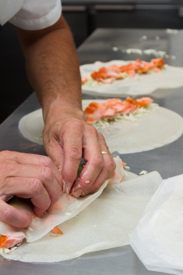 Executive chef rolling thin food shells with flavorful food ingredients to prepare for dinner service. Executive chef rolling thin food shells with flavorful food ingredients to prepare for dinner service