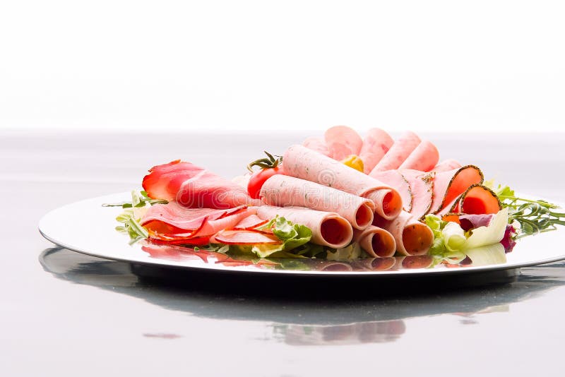 Food tray with delicious salami, pieces of sliced ham, sausage, tomatoes, salad and vegetable -