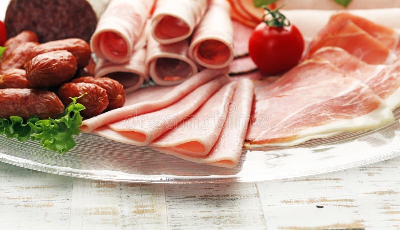 Food tray with delicious salami, pieces of sliced ham, sausage, tomatoes, salad and vegetable - Meat platter