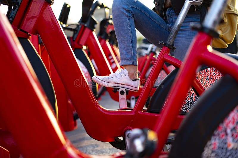 Foot climbing on a pedal of a red bike at a bike rental station royalty free stock images Foot climbing on a pedal of a red bike at a bike rental station royalty free stock images