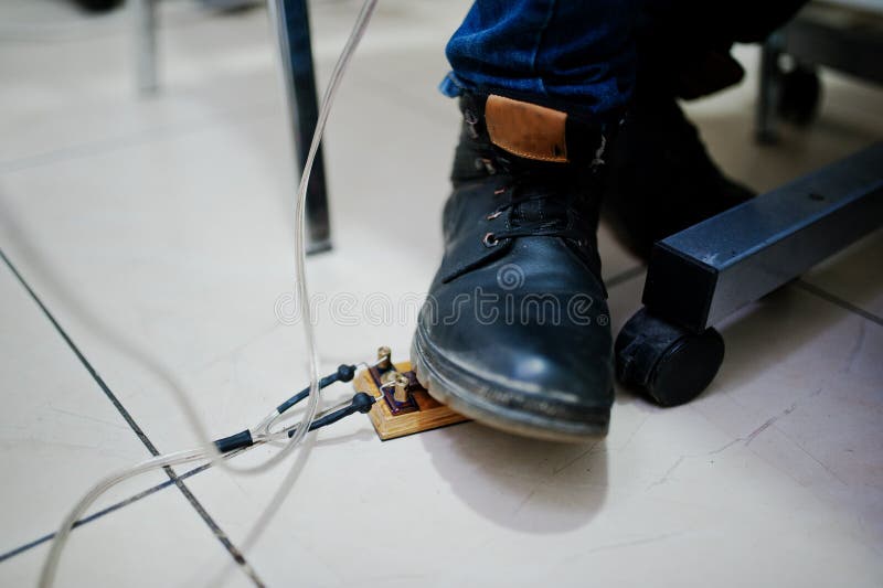 Foot on the Pedal of Tattoo Master at Tattoo Machine Stock Photo