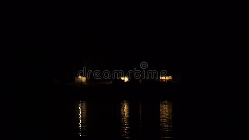 Footage a camp in the mountains, the light from the lights reflected on the water. 4K stock video
