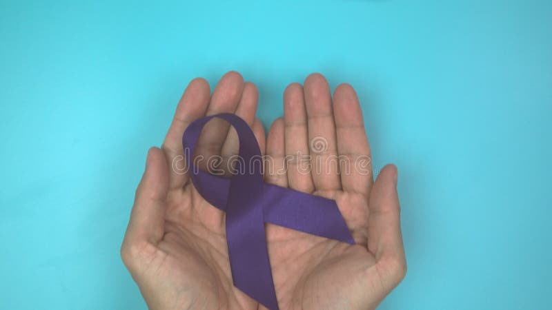 Footage video 4k. Hands holding purple or violet ribbon on blue. stock footage
