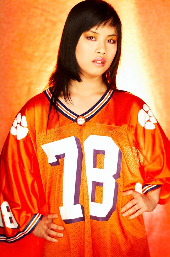Portrait of attractive beautiful young model with impressive makeup wearing orange sports football jersey. Portrait of attractive beautiful young model with impressive makeup wearing orange sports football jersey