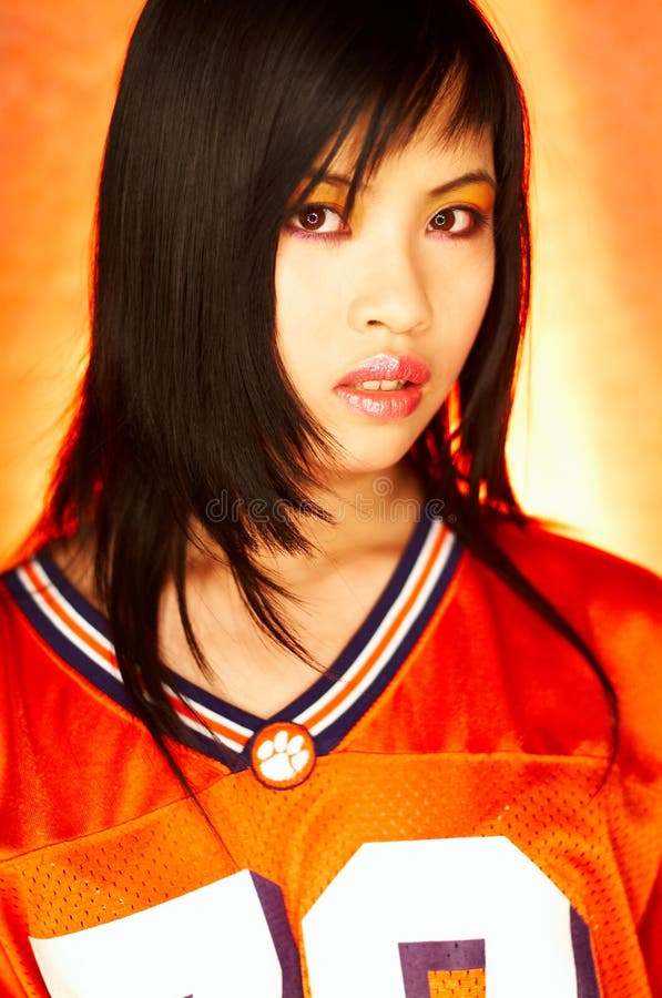 Portrait of attractive beautiful young model with impressive makeup wearing orange sports football jersey. Portrait of attractive beautiful young model with impressive makeup wearing orange sports football jersey