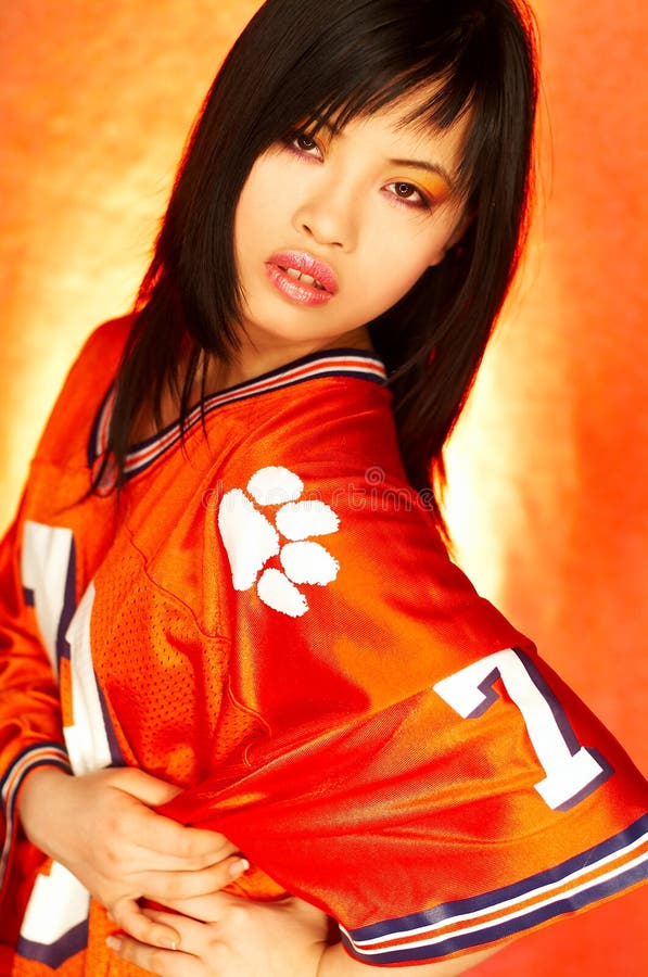 Portrait of attractive beautiful young model with impressive makeup wearing orange sports football jersey. Portrait of attractive beautiful young model with impressive makeup wearing orange sports football jersey