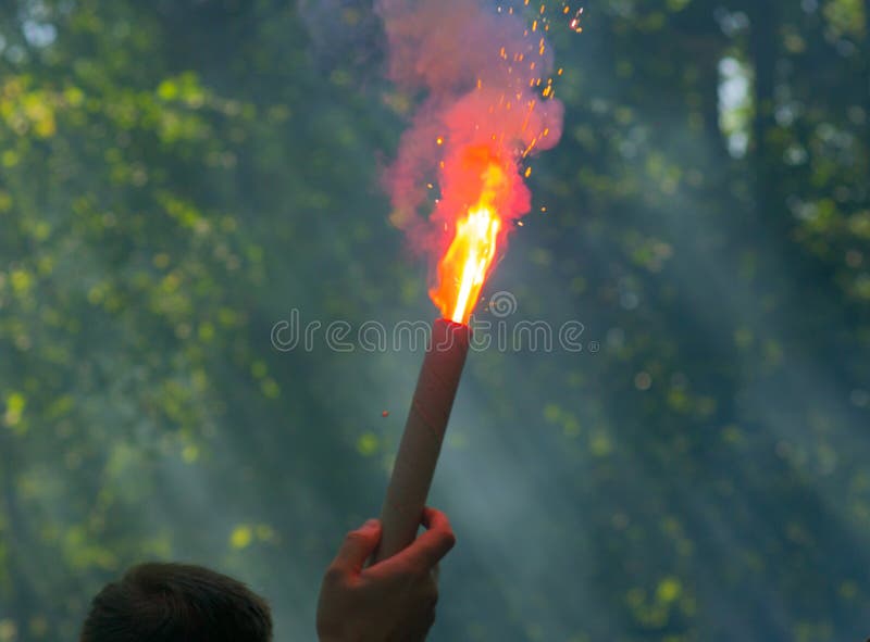 A football fan is holding a burning firecracker