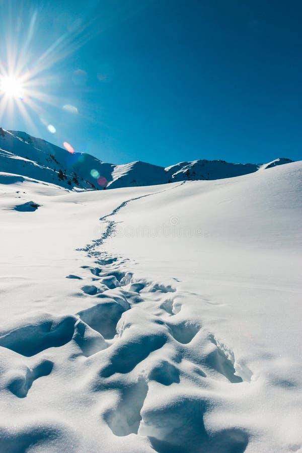 Footprints in the fresh snow mountains scenery. Beautiful winter sunrise. Adventure and travel time. Vertical.