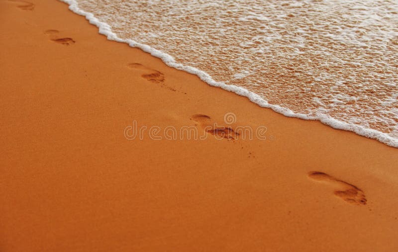 Footprints at golden sand, footsteps. Tropical beach with sea sand on summer vacation.