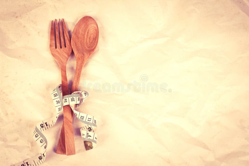 Forchetta di legno e cucchiaio di tono d'annata di colore legati con il rubinetto di misurazione immagini stock libere da diritti Forchetta di legno e cucchiaio di tono d'annata di colore legati con il rubinetto di misurazione immagini stock libere da diritti
