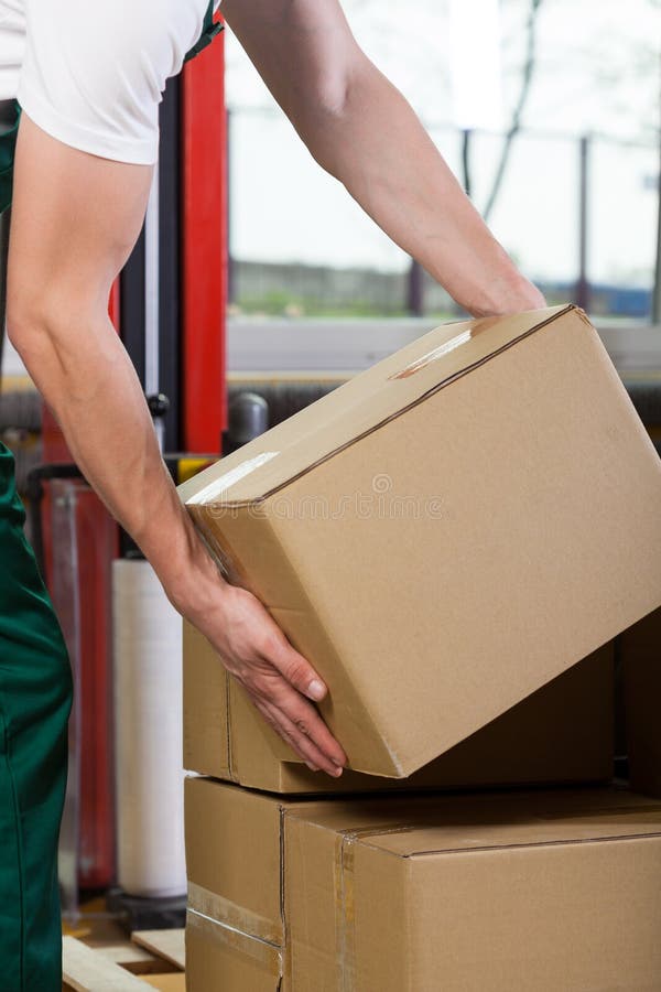 Foreman's hands lifting box at storehouse stock photography