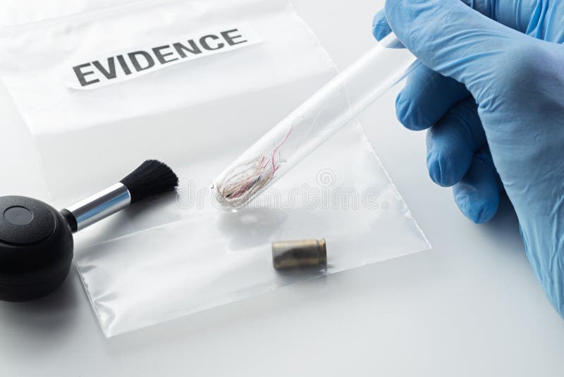 Forensic scientist`s hand holding glass tube over evidence bag next to brush