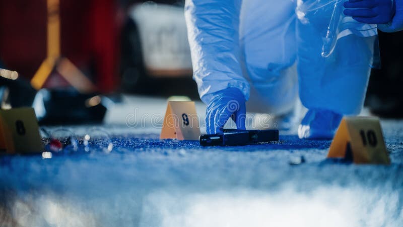 Forensics Working on Crime Scene at Night Gathering Evidence. Police Specialists Packing the Criminal&#x27;s Gun After Case of Gang Violence. Violent Incident of Mass Shooting and Homicide