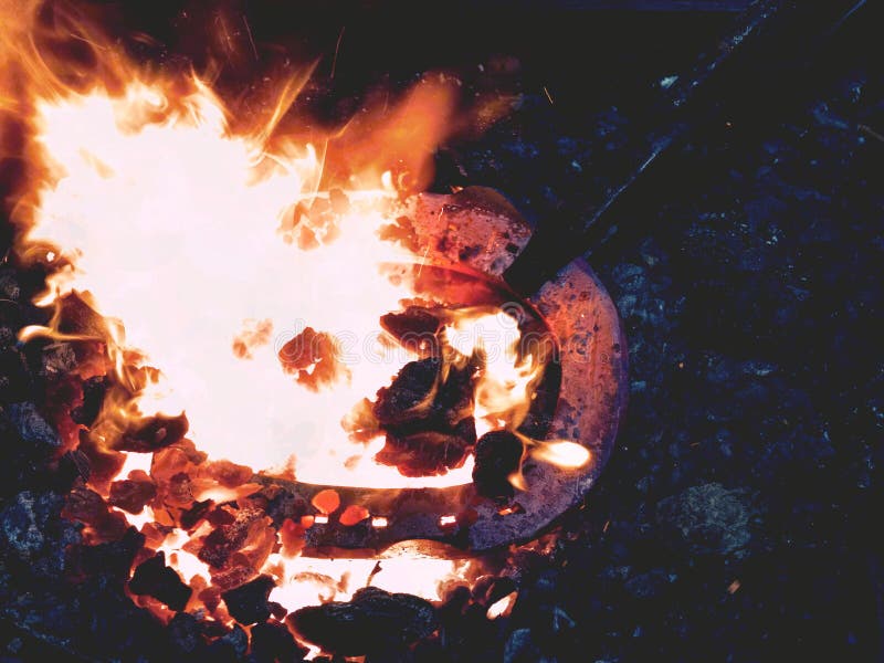 Forge avec les flammes fortes Les pinces tiennent la chaussure de cheval images libres de droits Forge avec les flammes fortes Les pinces tiennent la chaussure de cheval images libres de droits