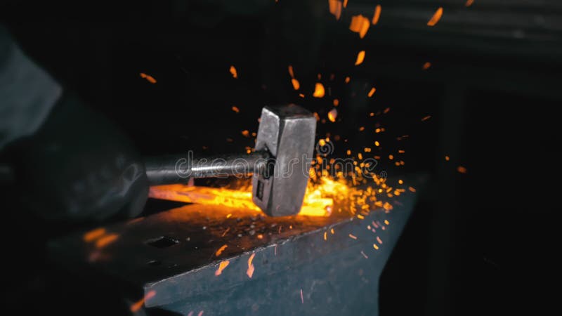 Forge workshop. Smithy manual production. Hands of smith with hammer hit on glowing hot metal, on the anvil, the forging