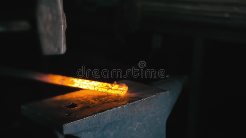 Forge workshop. Smithy manual production. Hands of smith with hammer hit on glowing hot metal, on the anvil, the forging