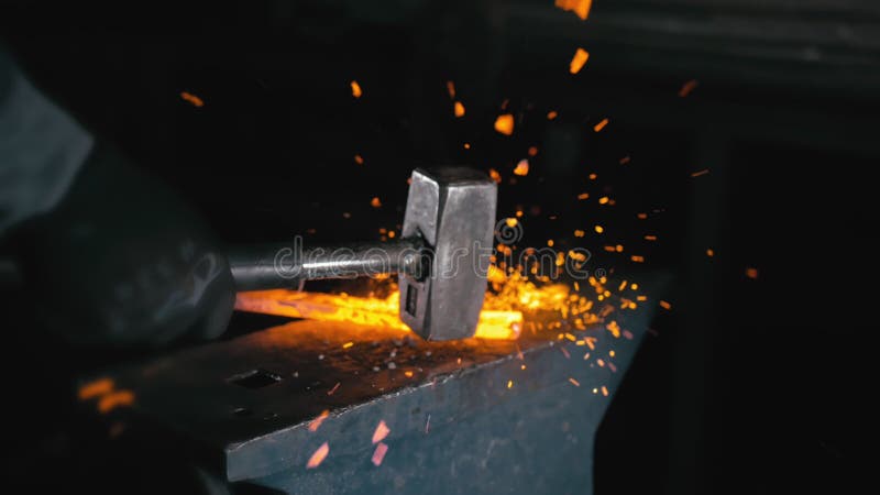 Forge workshop. Smithy manual production. Hands of smith with hammer hit on glowing hot metal, on the anvil, the forging