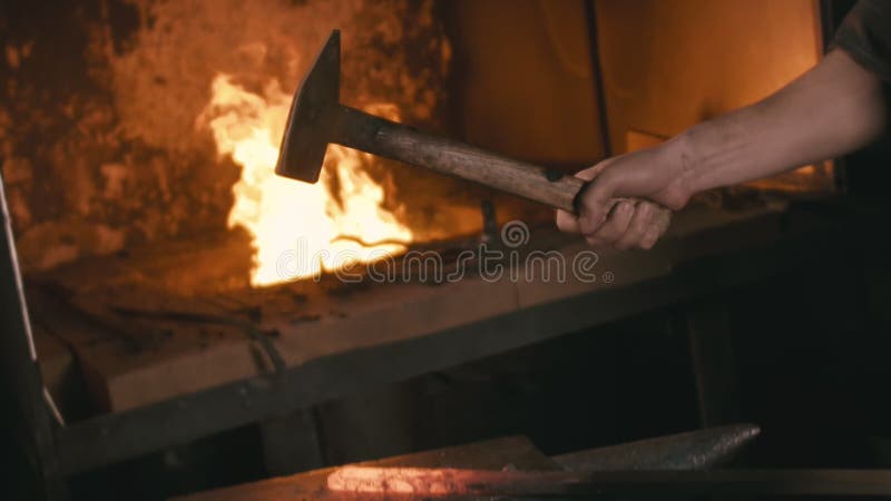 Forge workshop. Smithy manual production. Hands of smith with hammer hit on glowing hot metal, on the anvil, the forging