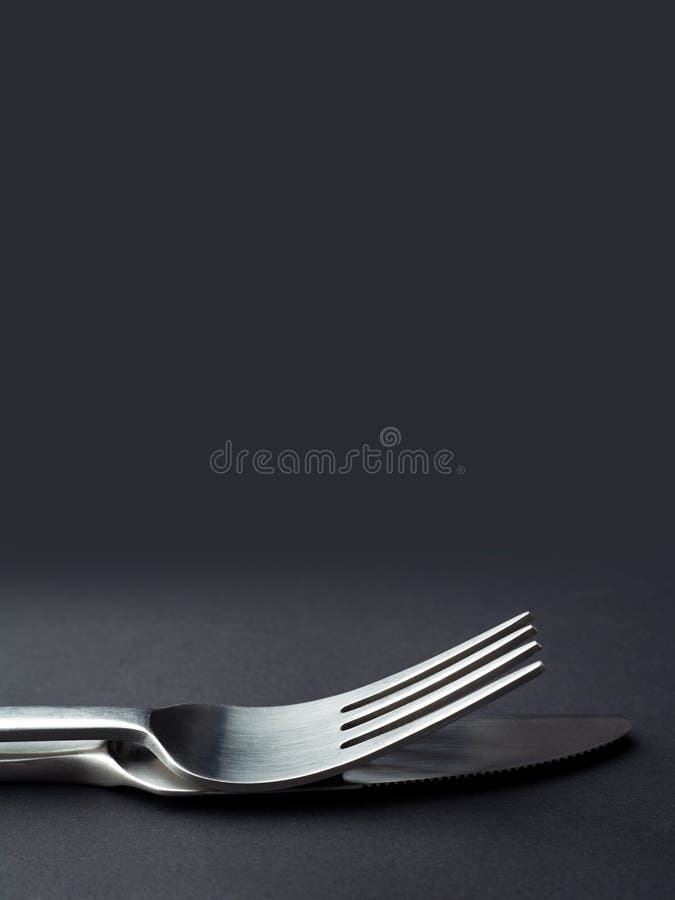 Fork and knife close up on a dark background with copy space