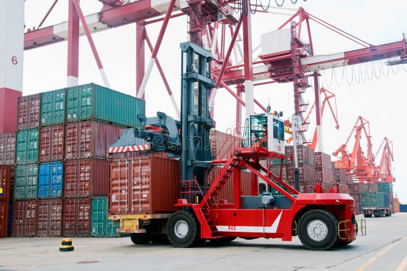 A forklift crane parked next to stacks of containers. A forklift crane parked next to stacks of containers