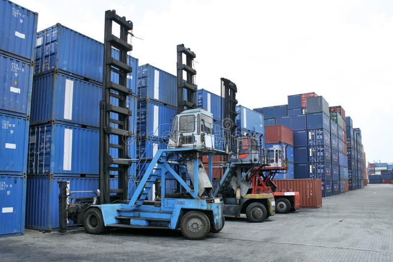 3 forklift cranes parked next to stacks of containers. 3 forklift cranes parked next to stacks of containers