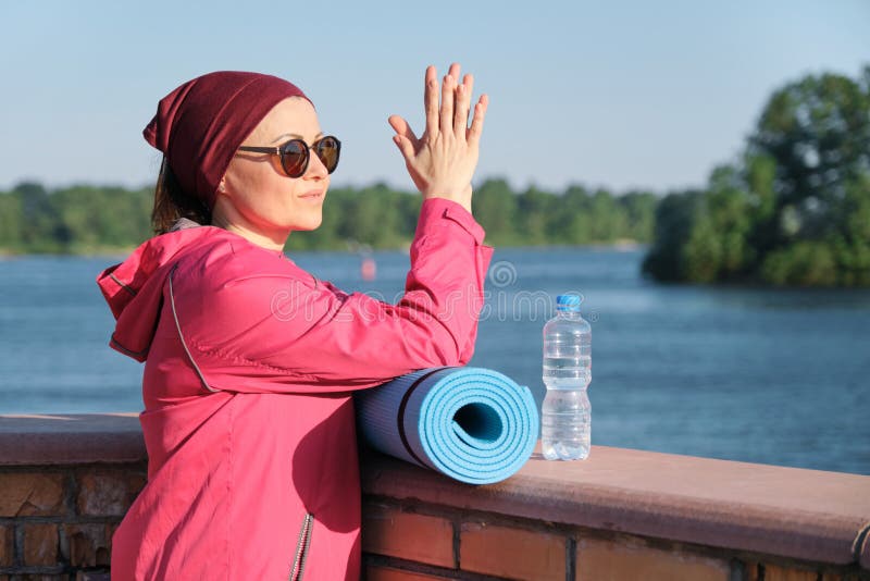 Forma de vida sana de la mujer madura, del retrato al aire libre de una hembra de la edad en ropa de deportes con la estera de la fotos de archivo Forma de vida sana de la mujer madura, del retrato al aire libre de una hembra de la edad en ropa de deportes con la estera de la fotos de archivo