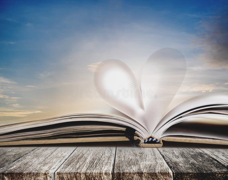 Forma del cuore alla pagina aperta del taccuino, sulla tavola di legno, con il cielo di tramonto nel fondo di estate, colori d'an fotografia stock libera da diritti