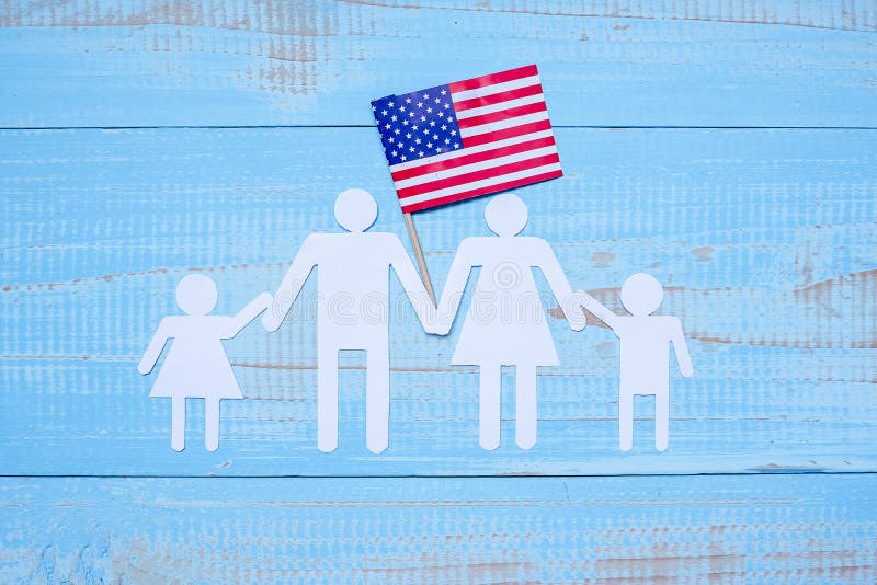 Forma del papel de la gente o de la familia con la bandera de los Estados Unidos de América en fondo de madera azul Día de fiesta fotos de archivo libres de regalías Forma del papel de la gente o de la familia con la bandera de los Estados Unidos de América en fondo de madera azul Día de fiesta fotos de archivo libres de regalías