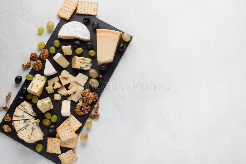 Formaggi assortiti con l'uva bianca, noci, cracker e su un bordo di pietra Alimento per una data romantica su un fondo leggero pr immagini stock libere da diritti Formaggi assortiti con l'uva bianca, noci, cracker e su un bordo di pietra Alimento per una data romantica su un fondo leggero pr immagini stock libere da diritti