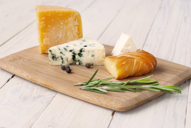 Formaggi di diverse varietà su una tavola di legno, di legno bianco Formaggi assordati su tavolette di legno Roquefort immagini stock Formaggi di diverse varietà su una tavola di legno, di legno bianco Formaggi assordati su tavolette di legno Roquefort immagini stock