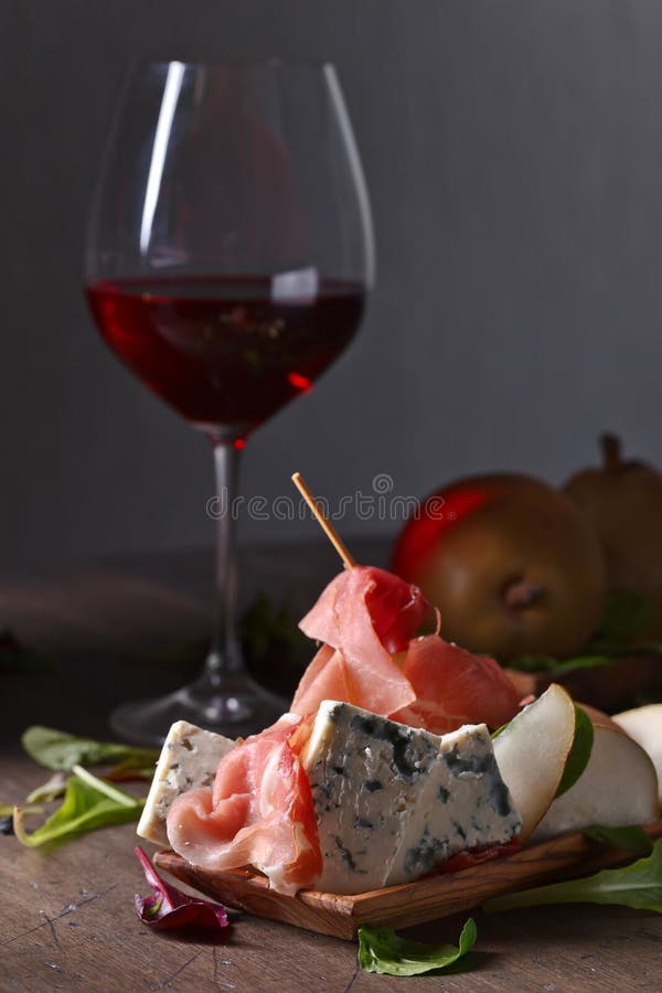Formaggio blu con il prosciutto di Parma, la pera ed il vino rosso fotografie stock Formaggio blu con il prosciutto di Parma, la pera ed il vino rosso fotografie stock