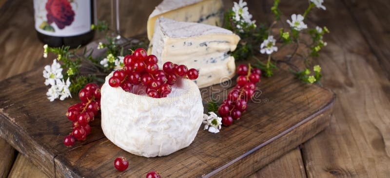 Formaggio differente con la muffa bianca e blu Un vetro di vino rosso e delle bacche fresche del ribes Fiori bianchi Fondo di leg fotografia stock libera da diritti