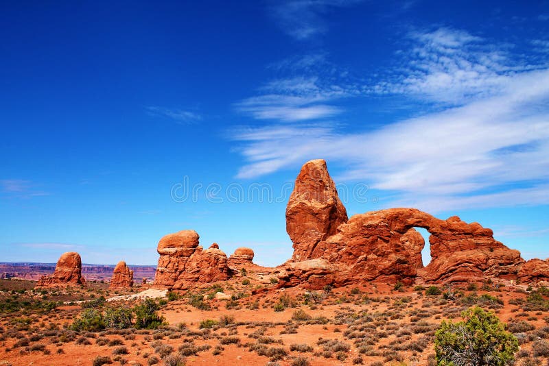 Formações de rocha irregulares com pináculos e arco, através de uma paisagem do deserto em Utá fotos de stock Formações de rocha irregulares com pináculos e arco, através de uma paisagem do deserto em Utá fotos de stock