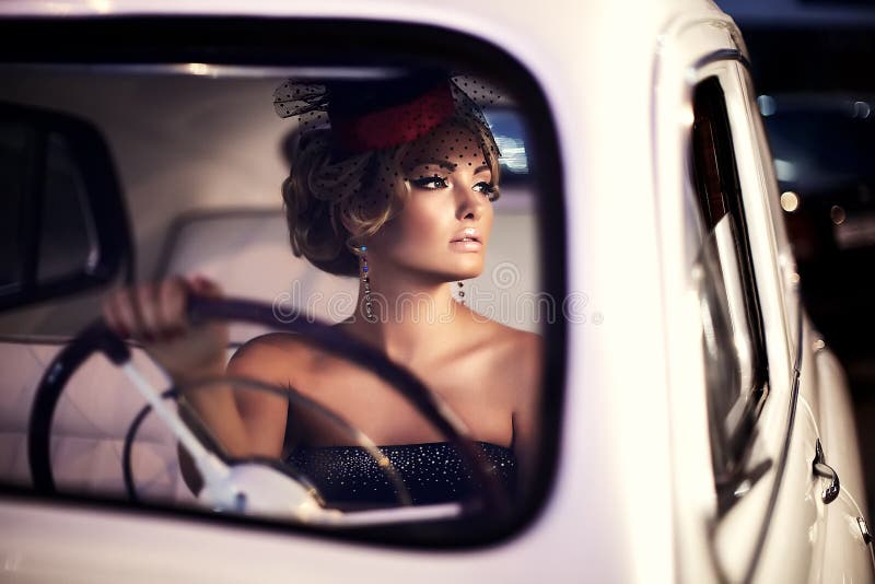 Forme a menina no estilo retro que levanta no carro velho foto de stock Forme a menina no estilo retro que levanta no carro velho foto de stock