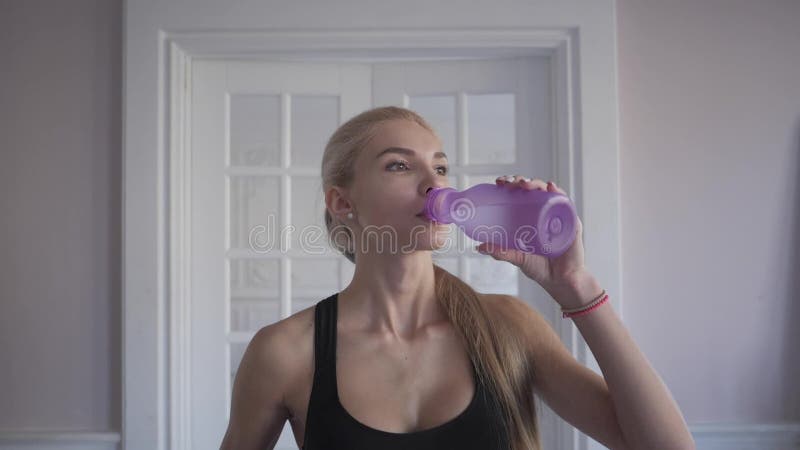 Forme physique à la maison eau propre de boissons d'une bouteille Faire de formation de jeune femme Près de l'hublot