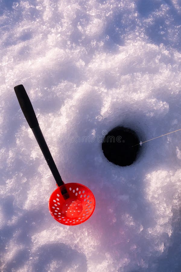 Ice fishing hole with fishing line and a plastic ladle for removing slush from the hole. Ice fishing hole with fishing line and a plastic ladle for removing slush from the hole.