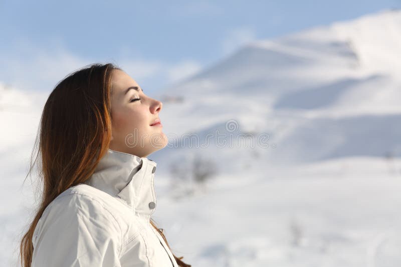 Forscherfrau, die Frischluft im Winter in einem schneebedeckten Berg atmet