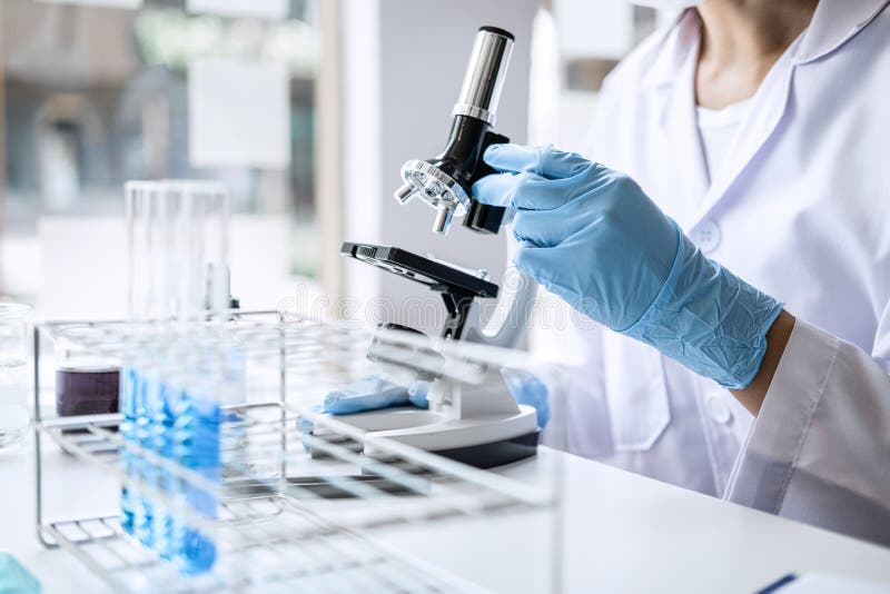 Forskare eller läkare i labblackering som arbetar i bioteknisk laboratorieutrustning för mikroskop för forskning med blandning av arkivfoton