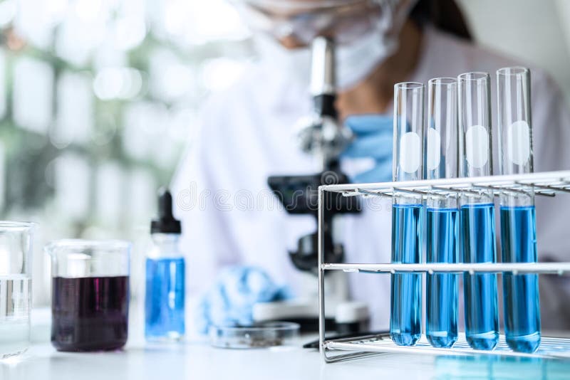 Forskare eller läkare i labblackering som arbetar i bioteknisk laboratorieutrustning för mikroskop för forskning med blandning av royaltyfri fotografi
