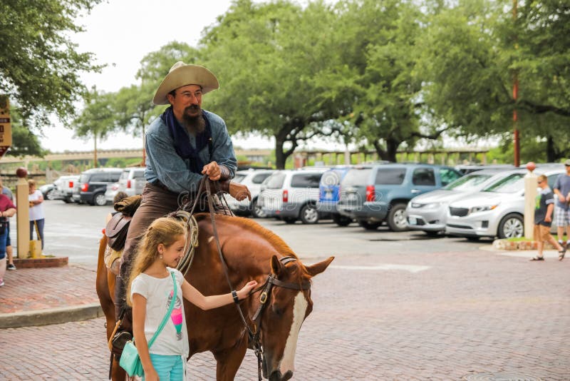 Fort Worth, Texas - June 19, 2017: A cowboy and a girl at the parade in Fort Worth Stockyards historic district. Longhorn cattle stock photos Fort Worth, Texas - June 19, 2017: A cowboy and a girl at the parade in Fort Worth Stockyards historic district. Longhorn cattle stock photos