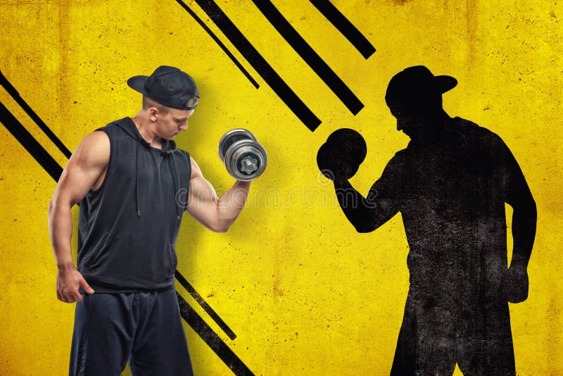 Forte giovane muscolare in abiti sportivi neri con una testa di legno con ombra nera su fondo giallo fotografie stock libere da diritti Forte giovane muscolare in abiti sportivi neri con una testa di legno con ombra nera su fondo giallo fotografie stock libere da diritti