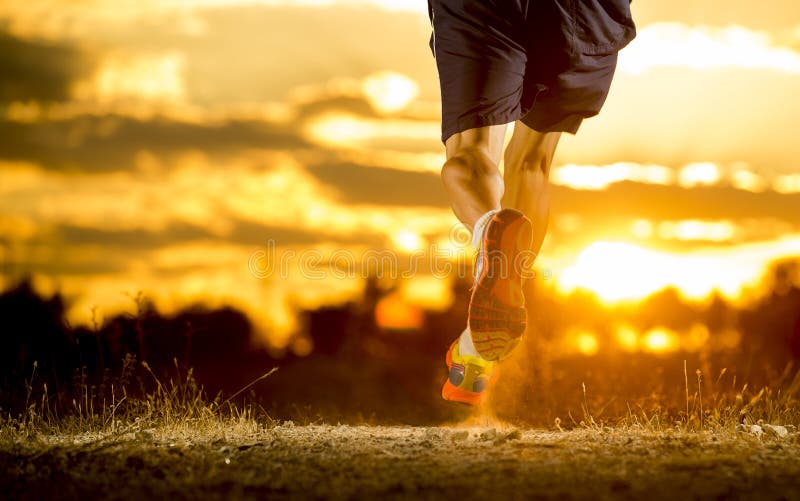 Forti gambe del giovane fuori da funzionamento della traccia al tramonto stupefacente di estate nello sport e nello stile di vita