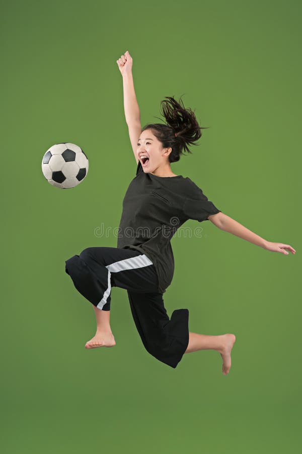 Forward to the victory.The young woman as soccer football player jumping and kicking the ball at studio on green royalty free stock photo Forward to the victory.The young woman as soccer football player jumping and kicking the ball at studio on green royalty free stock photo