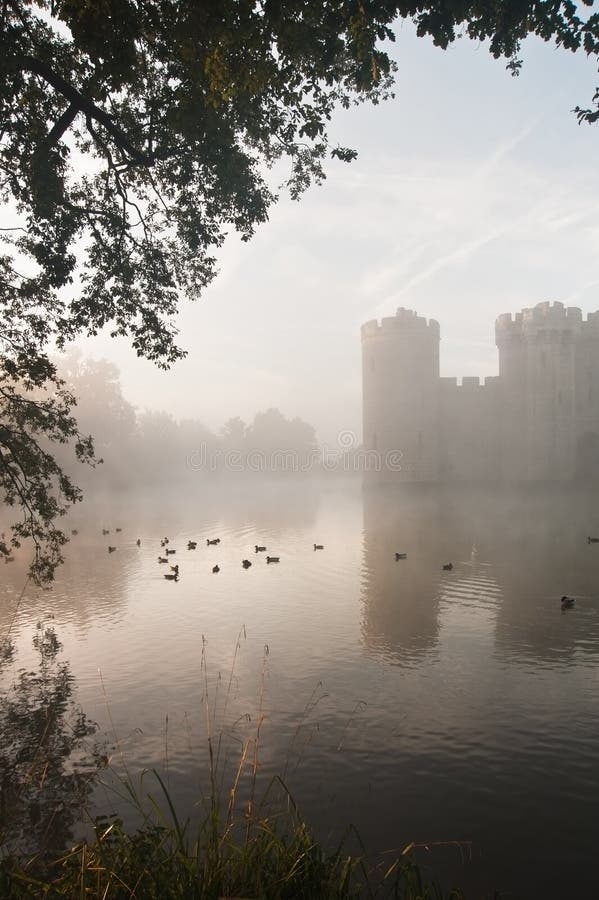 Fosso impressionante e castelo no nascer do sol da queda do outono com névoa sobre m