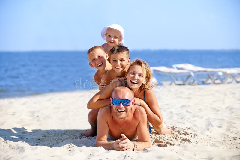 Fostra och avla med tre barn på stranden royaltyfri foto Fostra och avla med tre barn på stranden royaltyfri foto